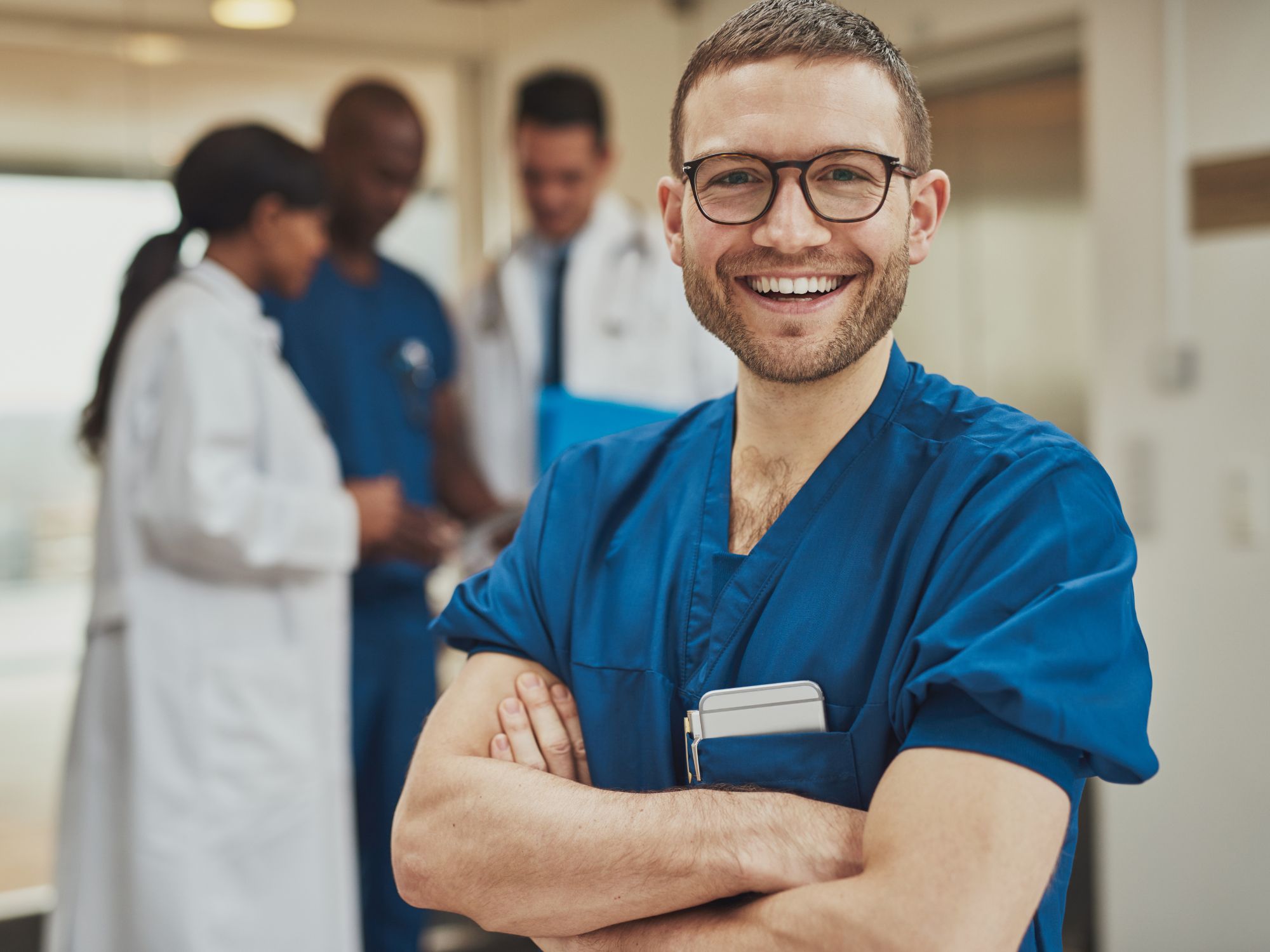 Smiling doctor with colleagues in background.