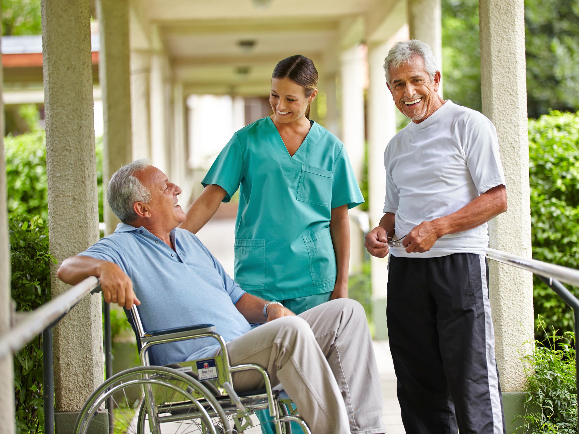 Nurse interacting with two elderly men outdoors.