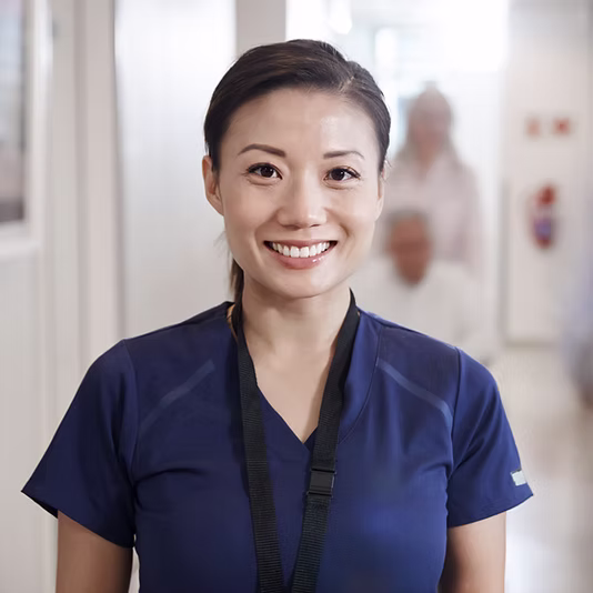Smiling nurse in hospital corridor.